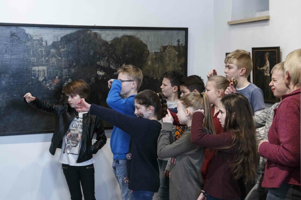 Een basisschool klas kijkende naar een schilderij door met hun vingers een deel van het schilderij af de dekken.