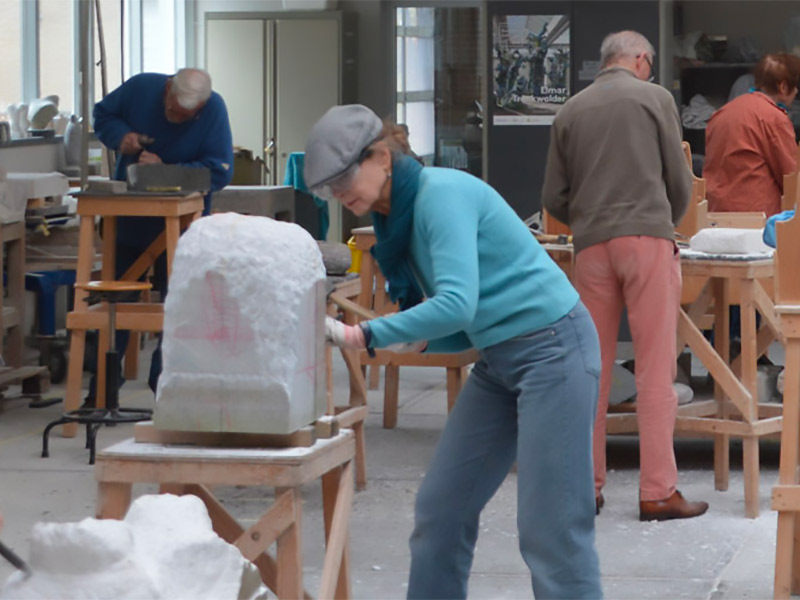 Mensen die in een atelier aan het beeldhouwen zijn.